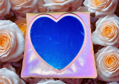 Gucci pink heart mirror with a glossy blue reflective surface surrounded by soft pink roses