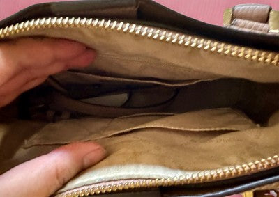 Inside view of a Michael Kors handbag bundle featuring multiple compartments and a spacious interior
